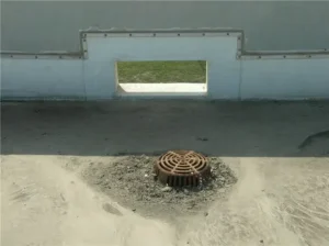 A box scupper next to a roof drain.