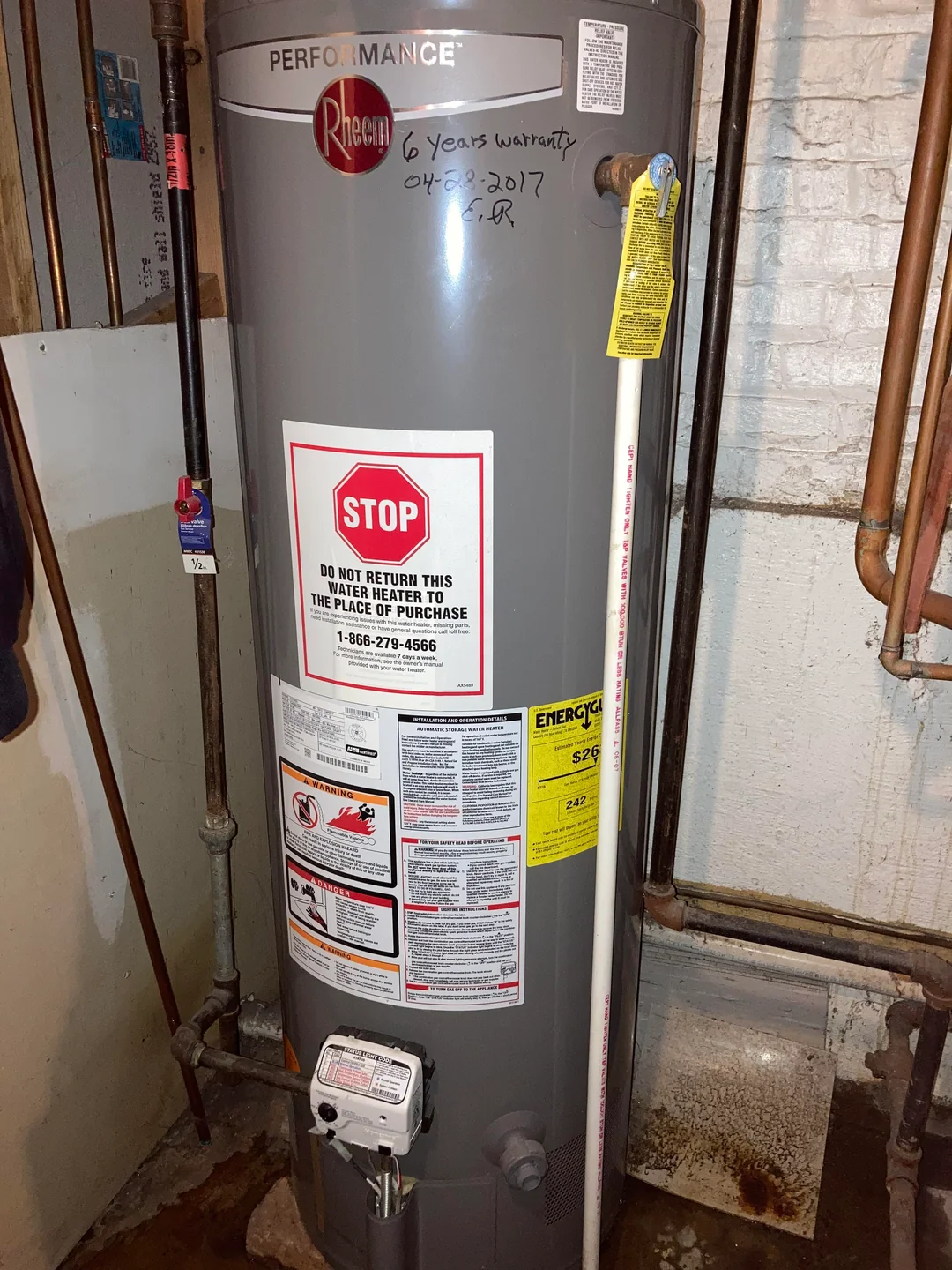 A water heater leaking from the pressure relief valve (the thin white PVC pipe) and unprotected by a drain pan.