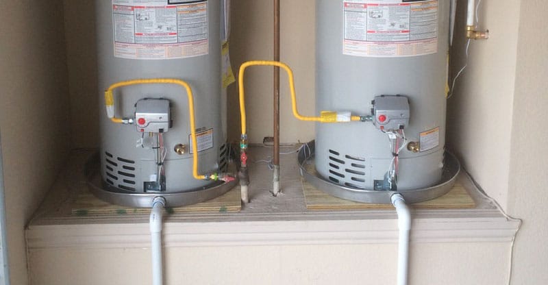 Two water heaters placed on water heater drain pans.